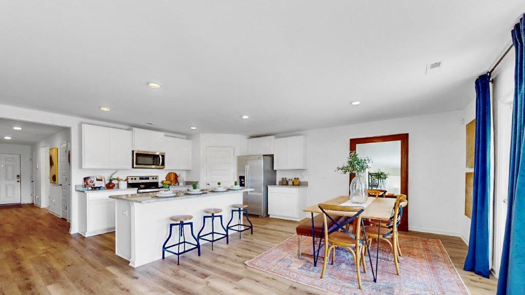 2. Cali – Living Room – 1- Bright open living room with a couch, 2 chairs, 2 poofs and amedia consol with flat screen television