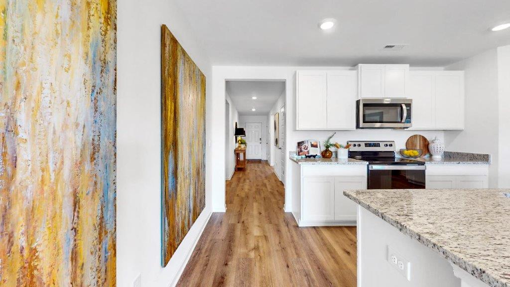 3. Cali – Living Room – 2 – Open living room with a couch, coffee table and 2 chairs and right off the living room is the door to the primary bedroom