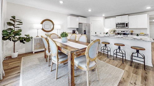 an open concept dining room that features a large dining table, and a breakfast consol that opens to the oversized kitchen