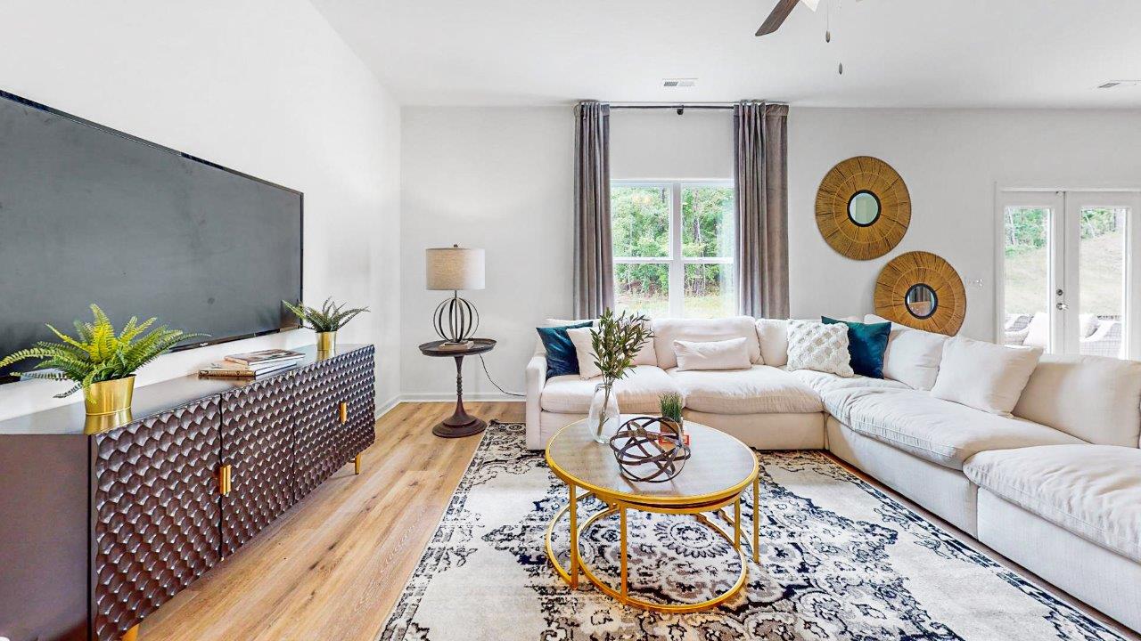 3. Elston – Living Room – 2 – another view of the living room that shows the sectional couch as well as a coffee table and media consol with flat screen television