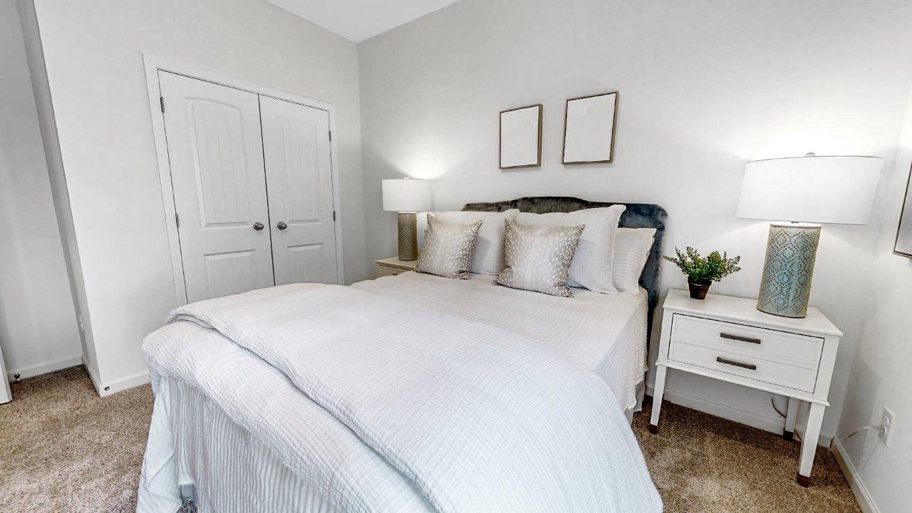 The alternate view of the second bedroom displays the bed and the double doors of the closet.
