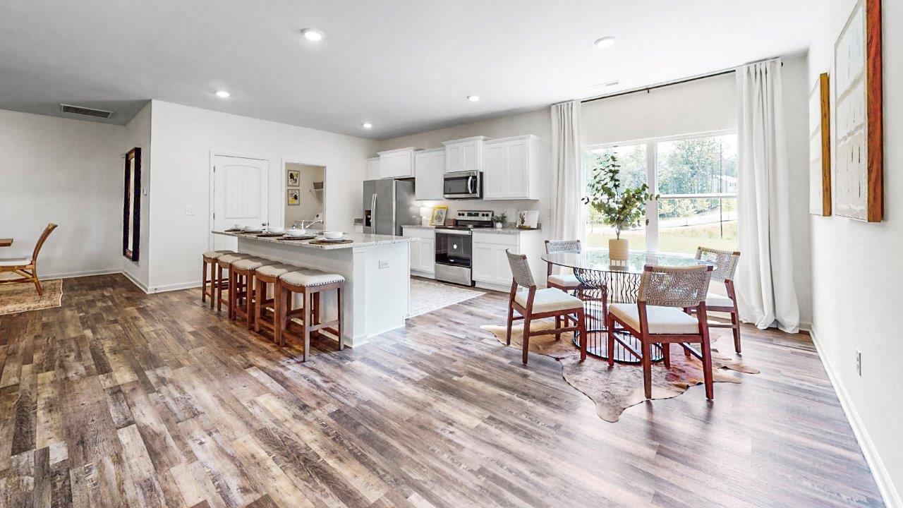 Spacious modern living room with cozy beige sectional sofa and colorful cushions, elegant wooden flooring, wall-mounted TV, stylish decor, and an adjacent dining area with a wooden table and chairs, creating an inviting open-concept layout.