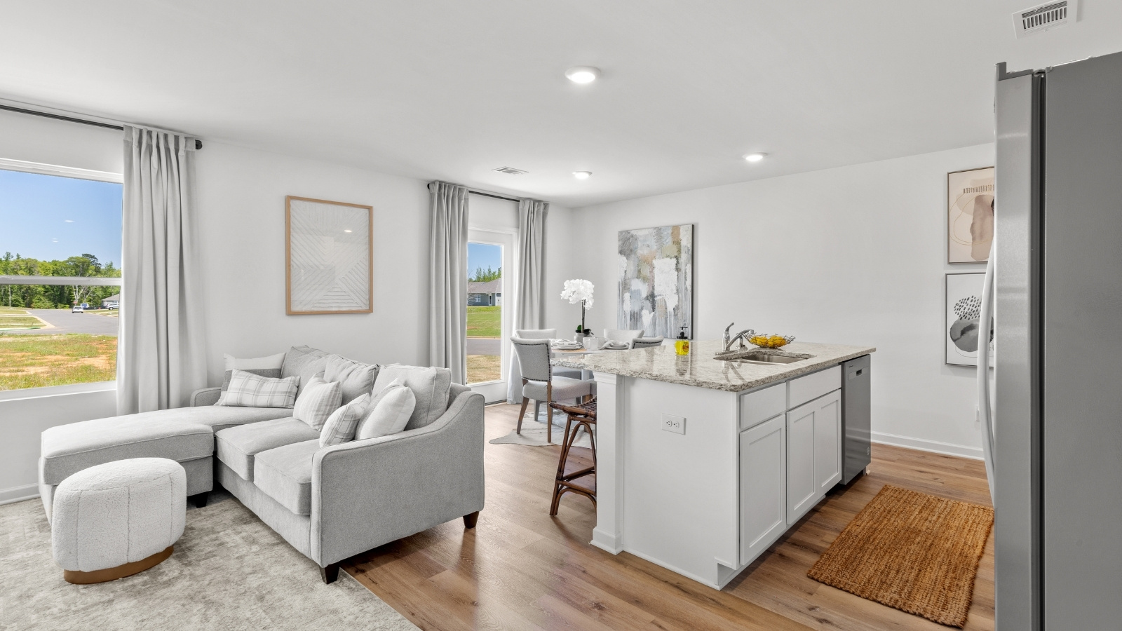 The open concept kitchen features a large counter island connected to the wall with granite counter tops and stainless-steel appliances.
