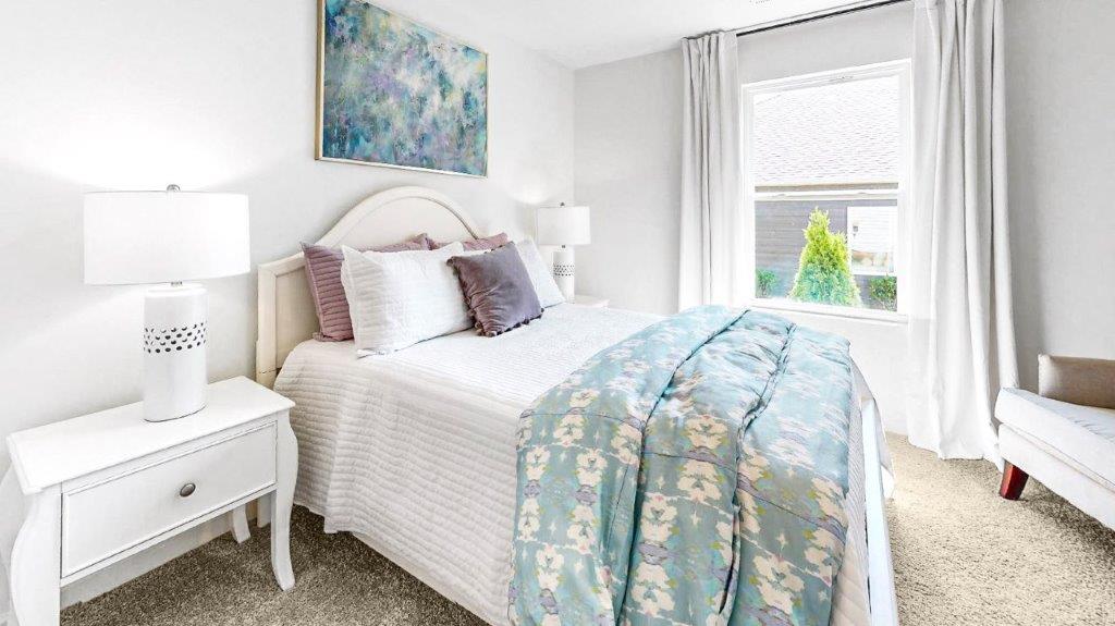 the second bedroom features a bed with 2 nightstands, a large window and accent chair