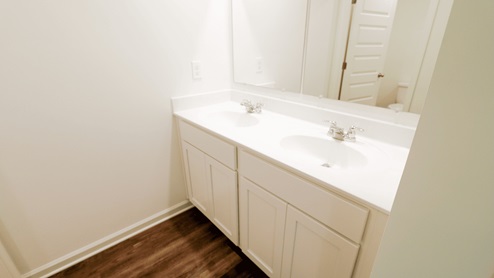 Double vanity bathroom with white cabinetry, two sinks, and a large mirror against a light-colored wall.