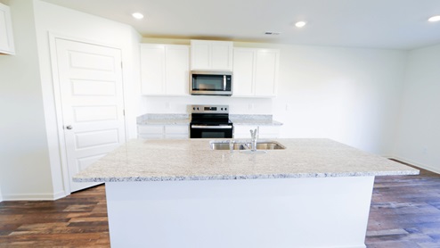Modern kitchen with granite countertops, white cabinets, and stainless-steel appliances, designed for functionality and style.