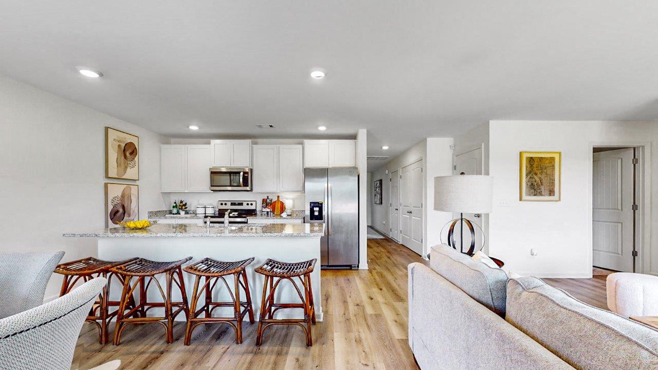 The open concept kitchen features a large counter island connected to the wall with granite counter tops and stainless steel appliances