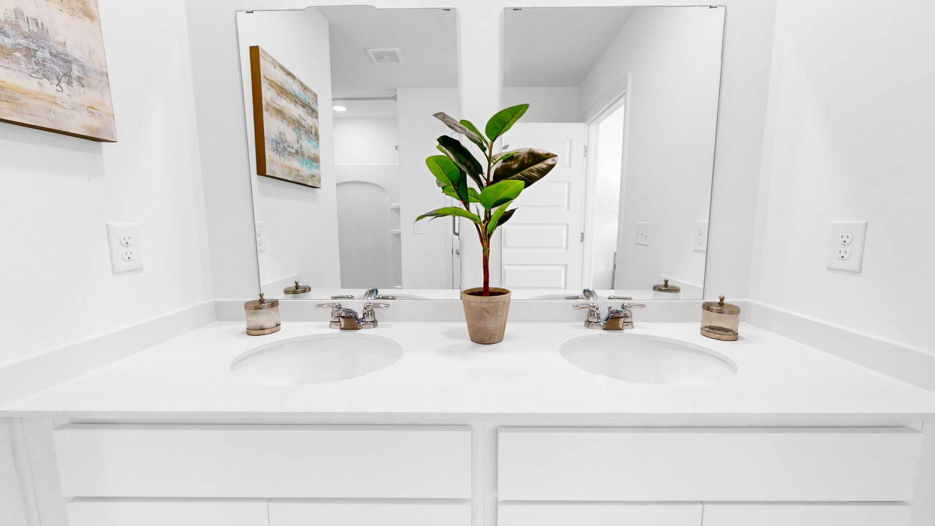 The bathroom features two sinks and a plant, creating a refreshing and functional space.
