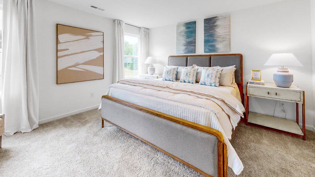 Cozy primary bedroom with large king size bed, 2 nightstands and a stylish dresser for storage