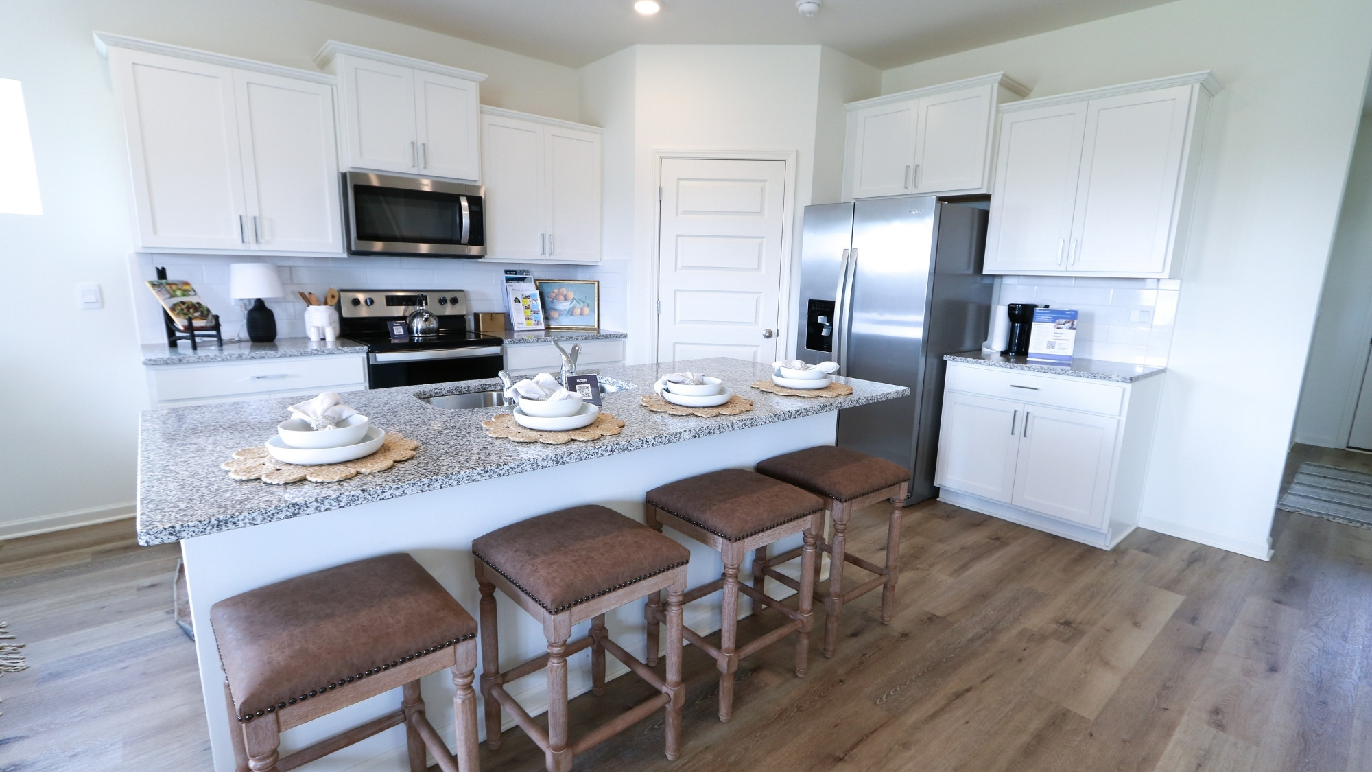 The large island hosts a stainless steel sink and room for 4 barstools.