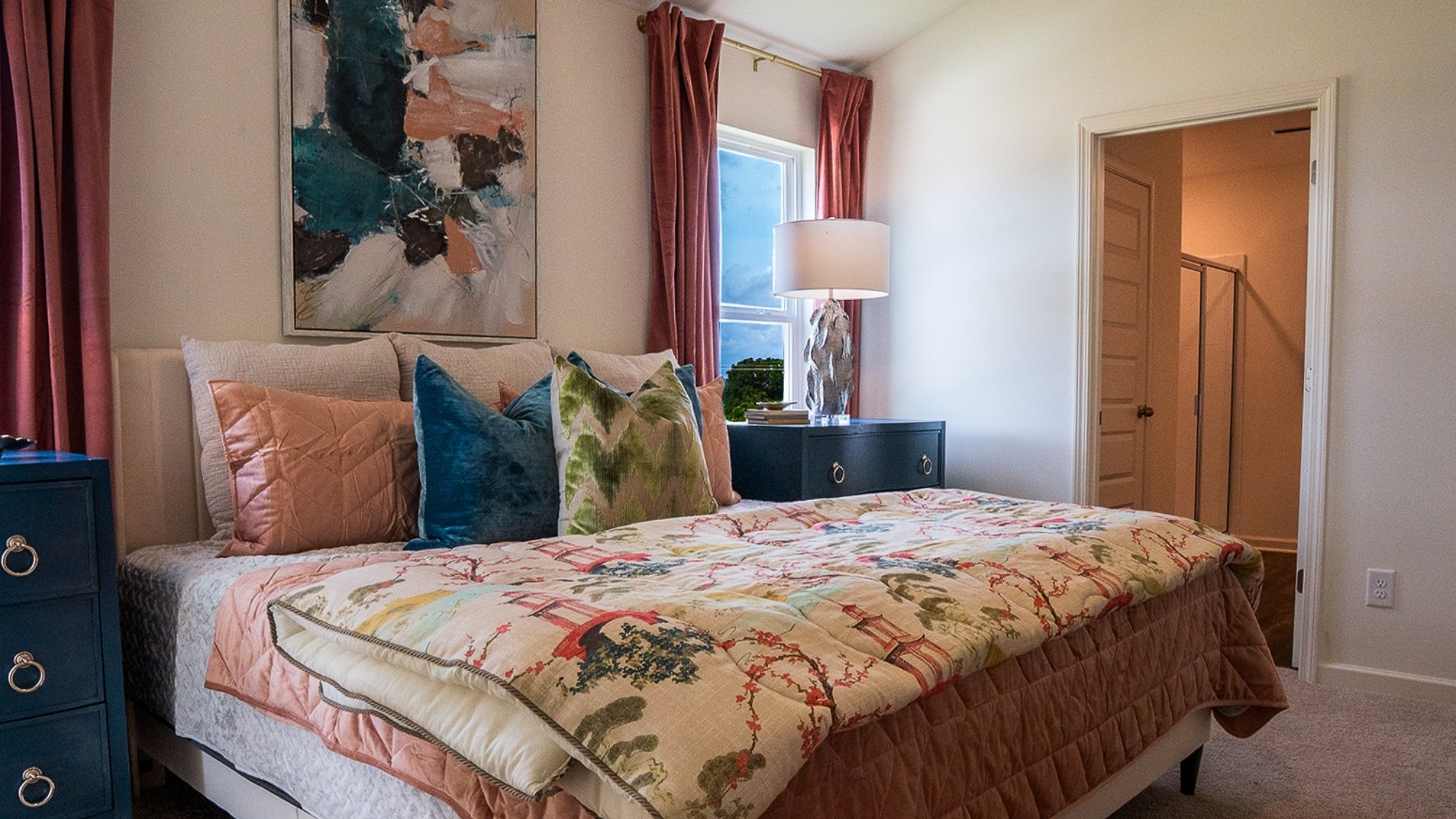 The second bedroom is shown here staged with a queen sized bed, two nightstands, and an armchair.