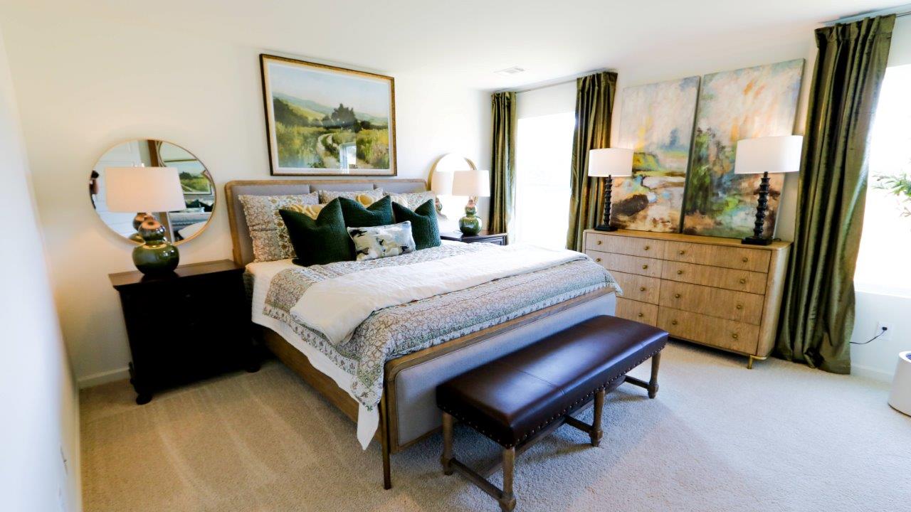 The primary bedroom features ample space for a queen bed, 2 nightstands, and a large dresser  with large windows allowing natural light to fill the whole space.