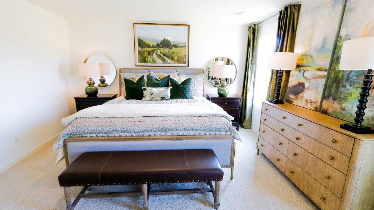 The primary bedroom is shown here staged with a full collection of bedroom furniture, and features a large amount of natural light streaming through the large windows.