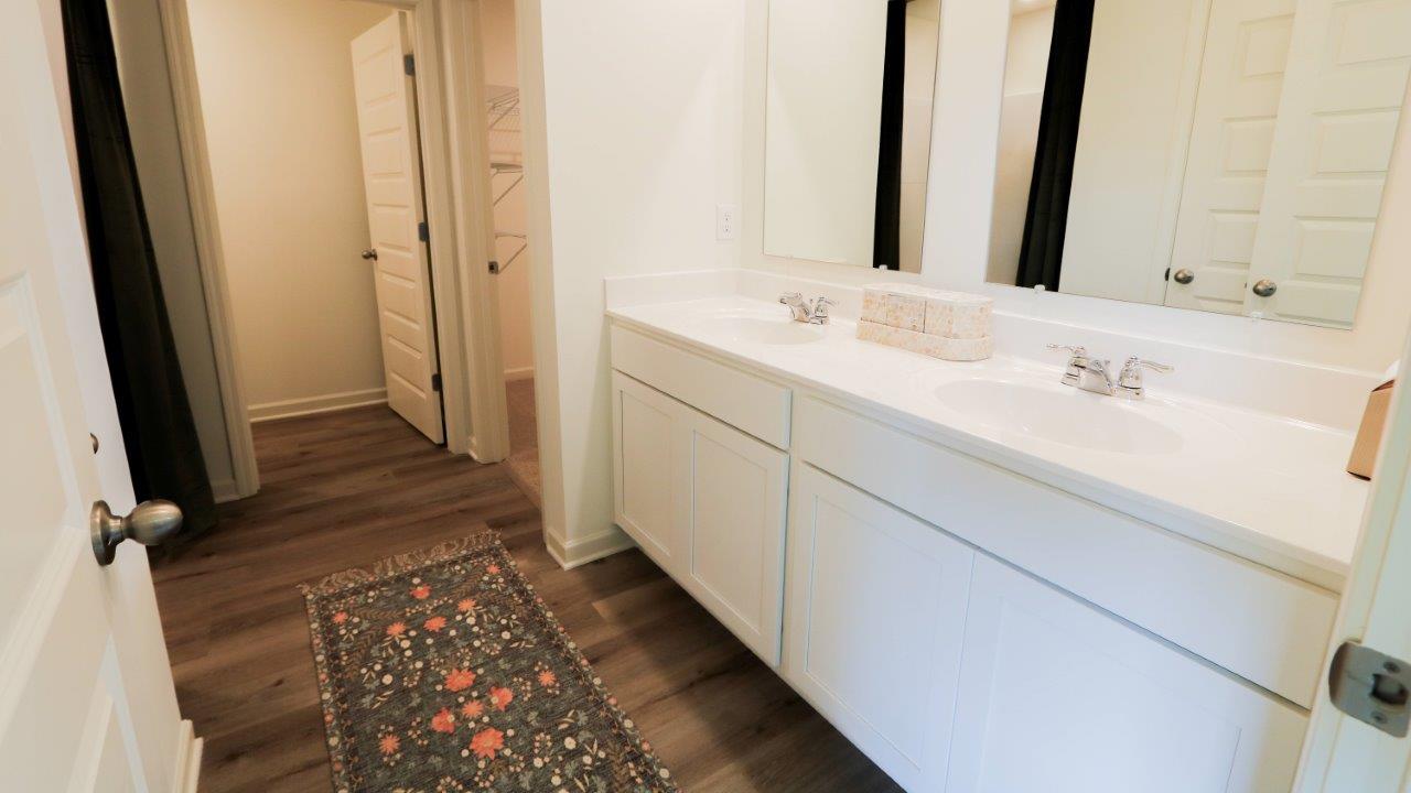 The spacious primary bathroom features modern fixtures and a beautiful wood-finish flooring.