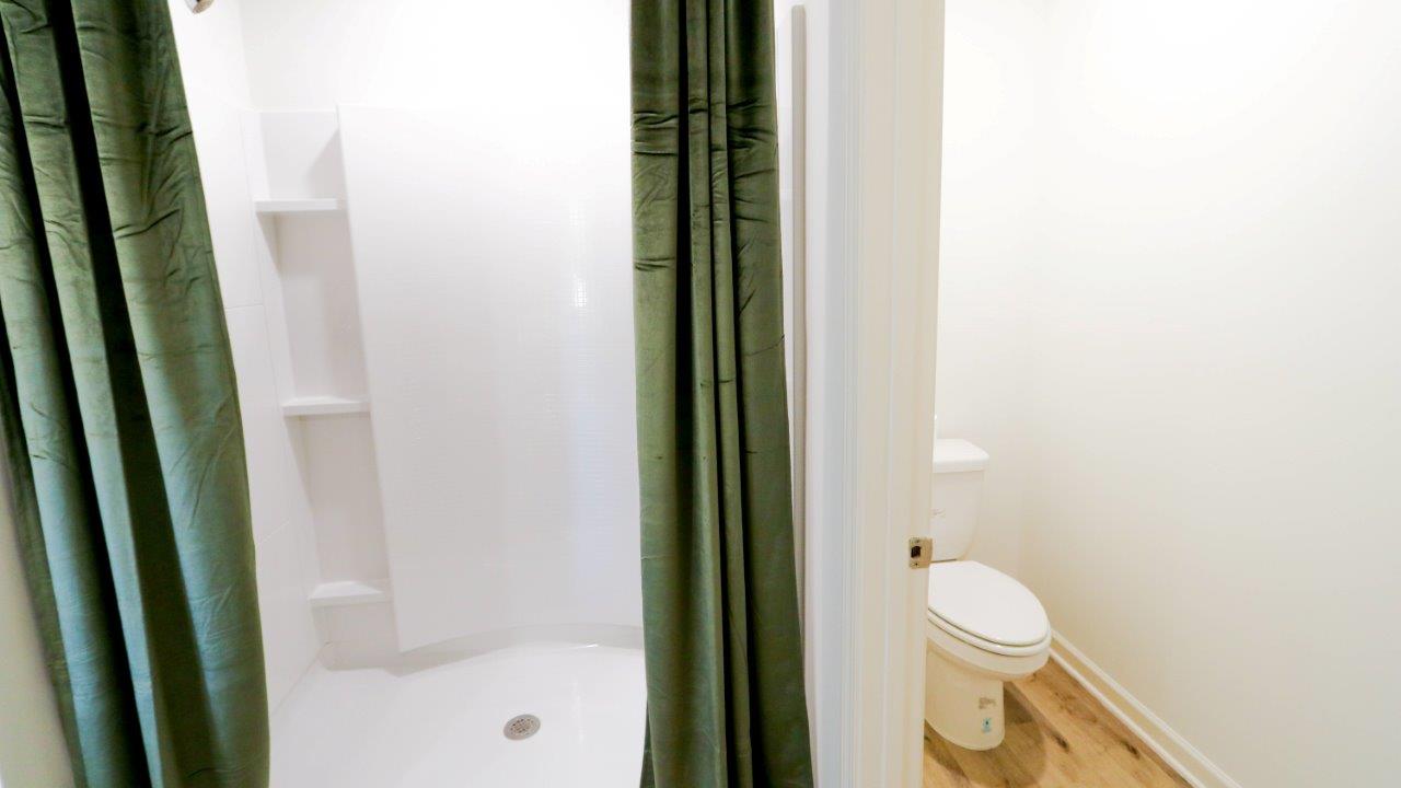 The spacious shower features storage space for toiletries, with the toilet nestled into an adjacent nook.