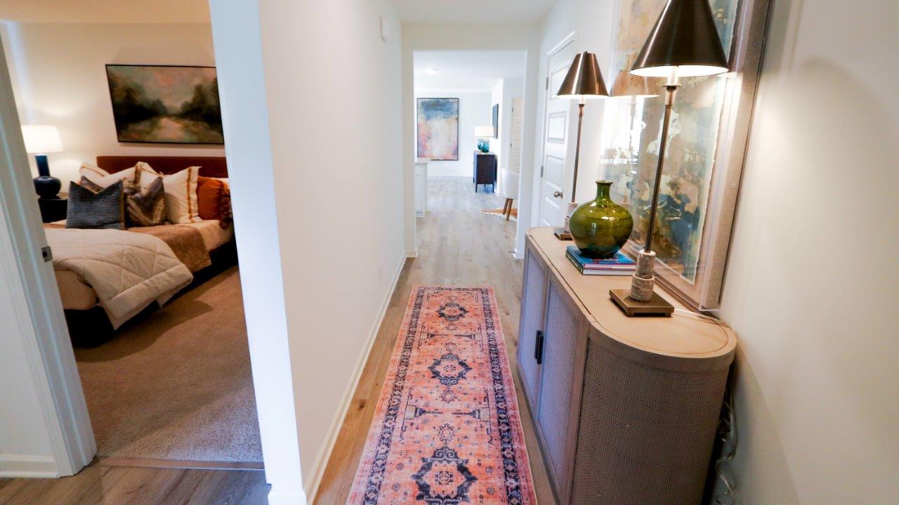 A view down the hallway, leading from the entrance, with a peek into one of the bedrooms. Lots of natural light is available throughout.