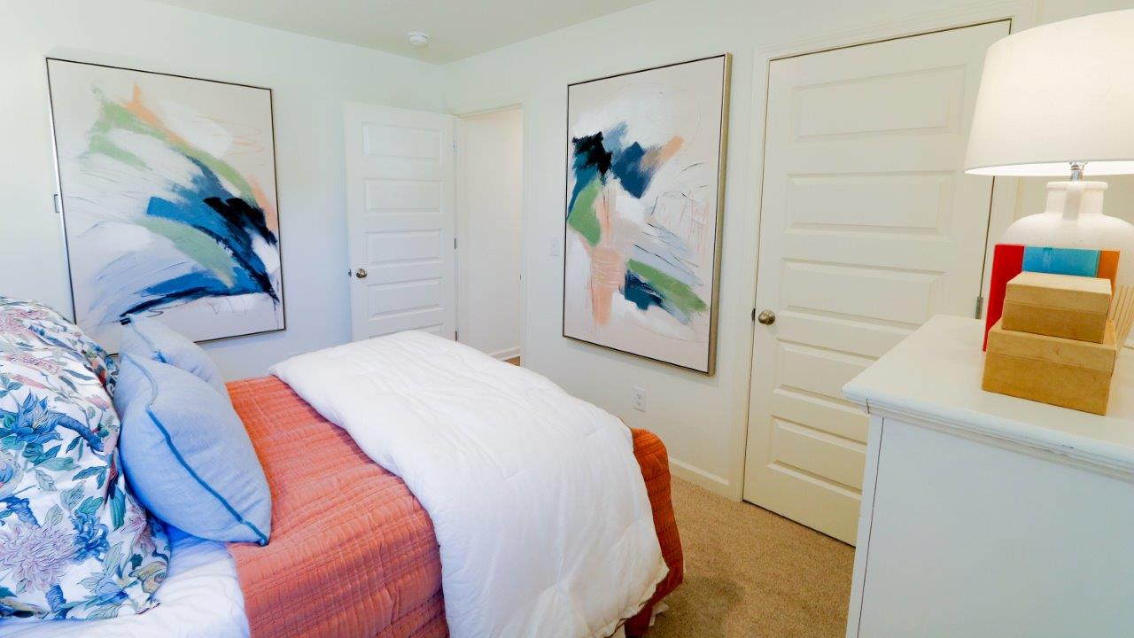 The third bedroom is shown here staged with a full sized bed and a spacious dresser, all finished with modern finishings and lush carpet.