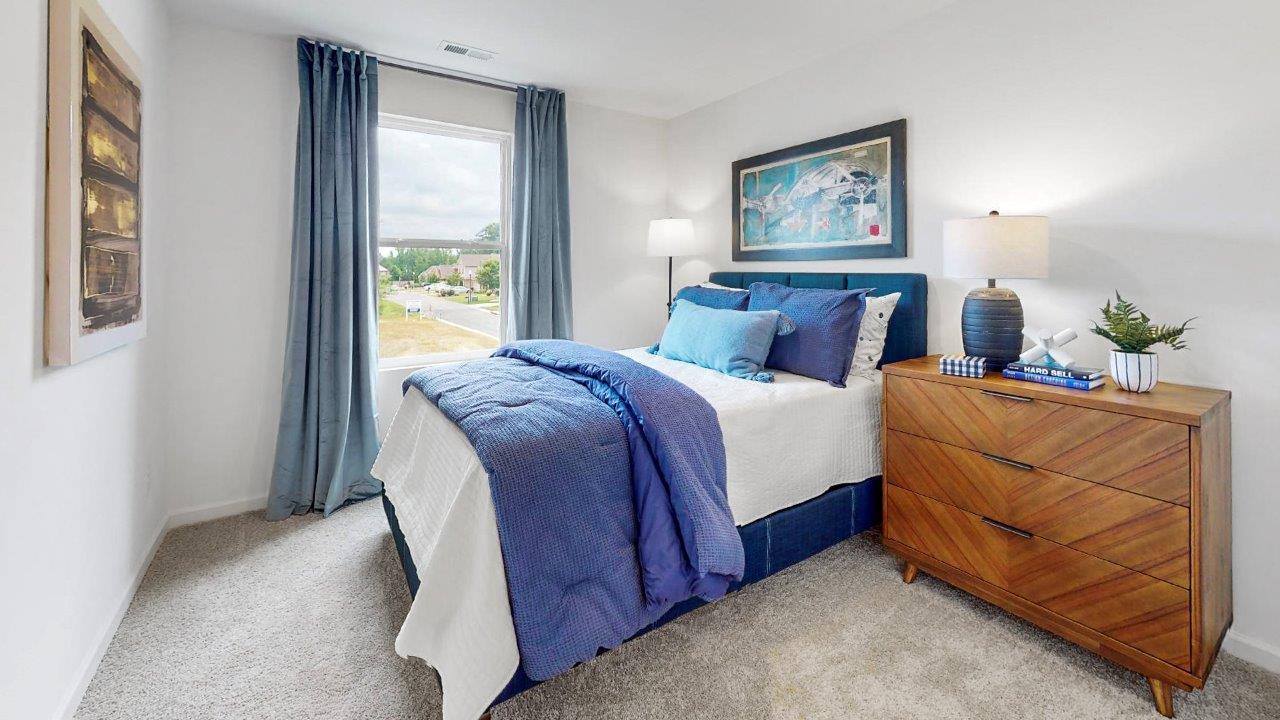 A tranquil bedroom showcasing a full-size blue bed alongside a modern dresser, perfect for relaxation and comfort.