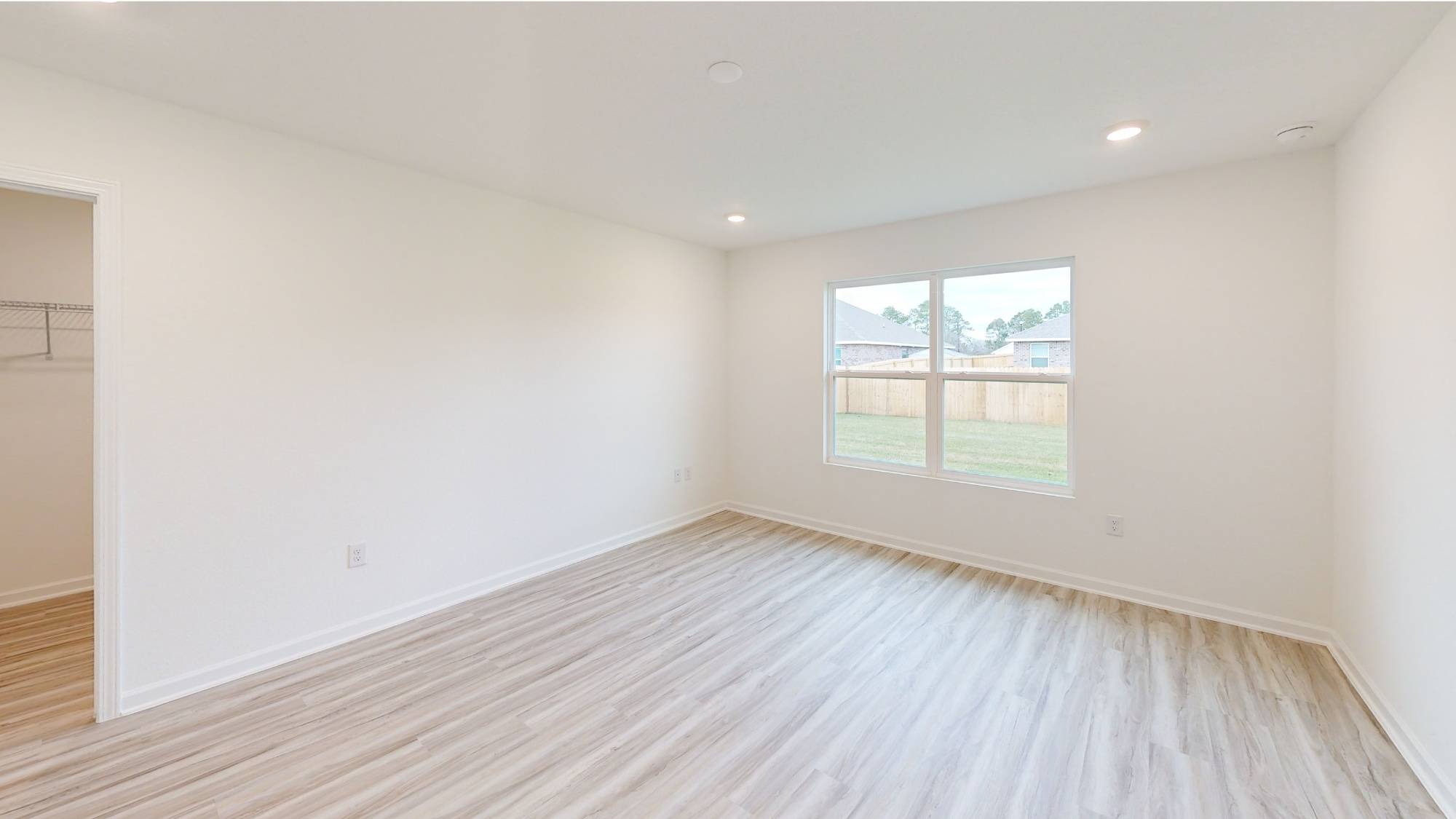 The primary bedroom has a large window which looks out over the backyard. The room has space for a king sized bed, two nightstands, and a dresser.