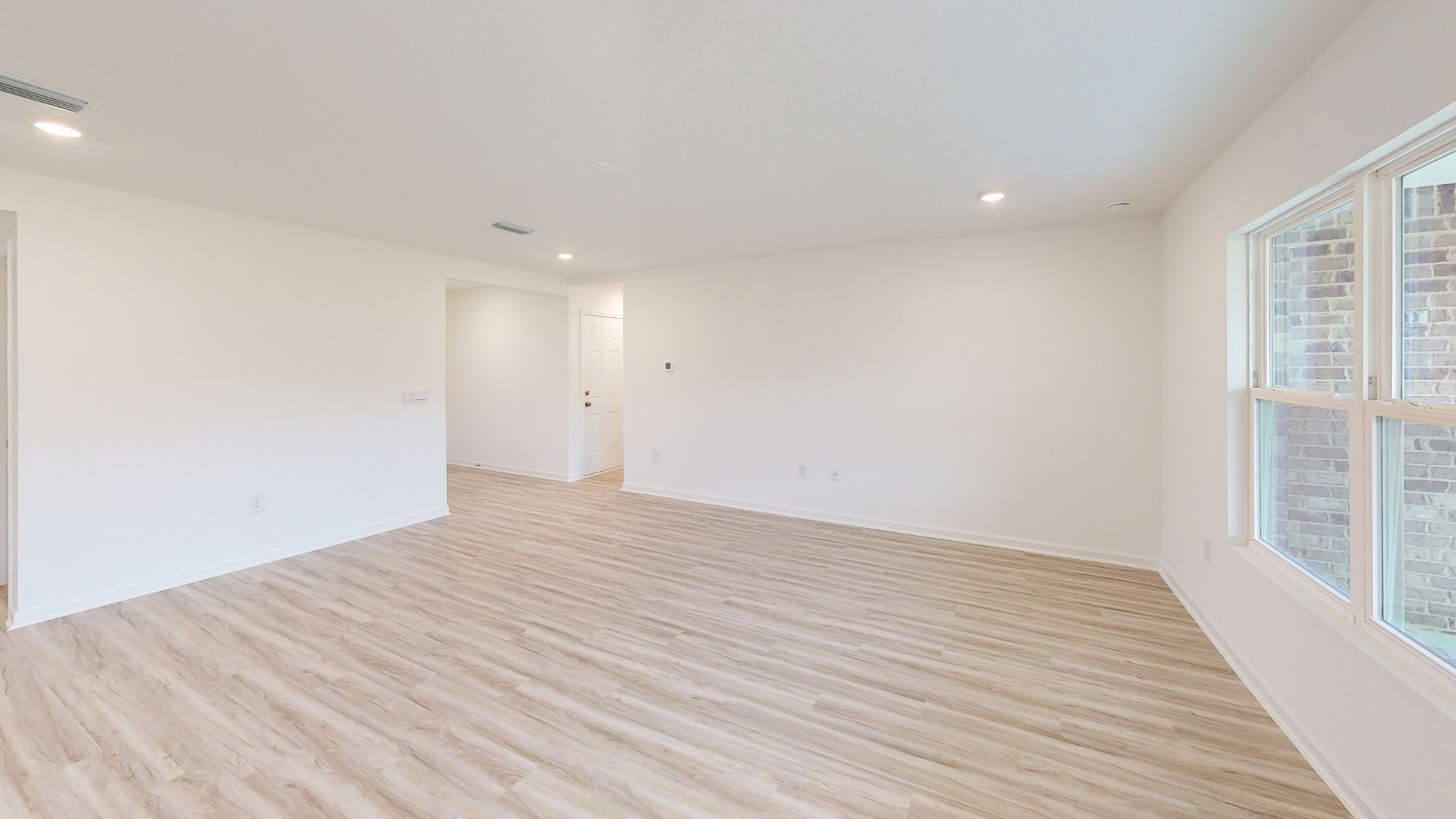 Living room bathed in natural light, with room for a full set of living room furniture and a spacious, open-concept layout.