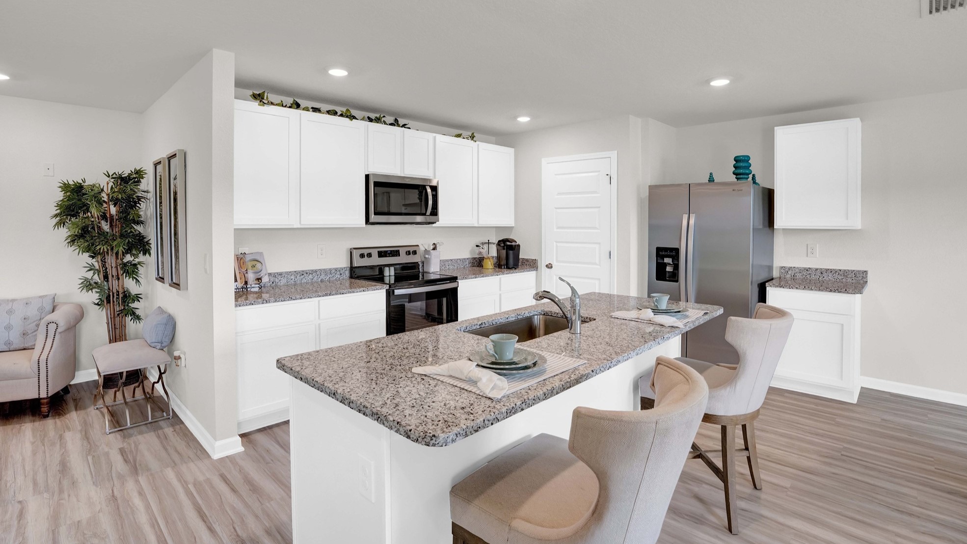 The kitchen is a spacious open concept area with stainless steel appliances. It includes an oversized kitchen island with barstools for seating and food preparation. Additionally, there is a convenient walk-in pantry for storage.