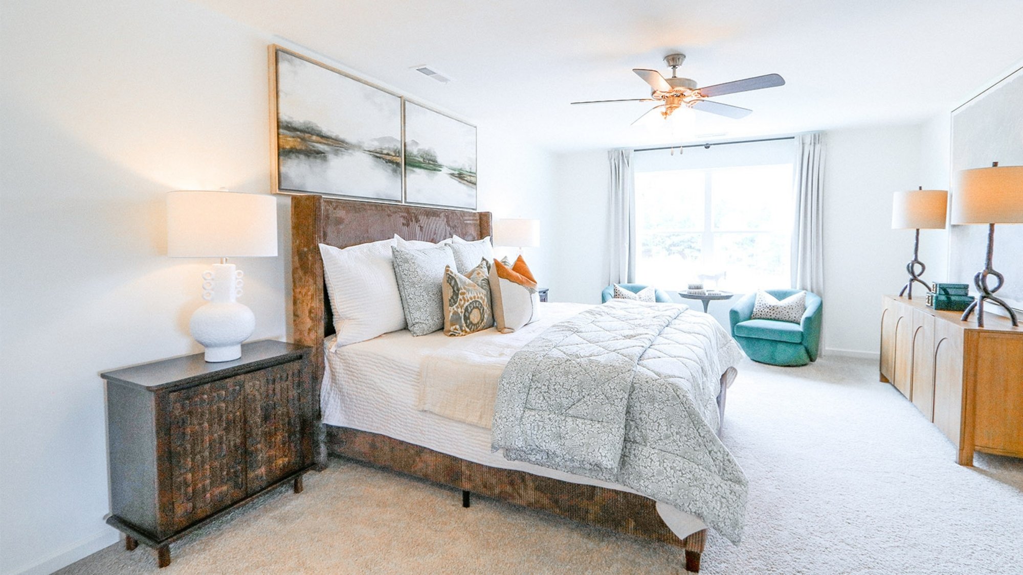 The expansive primary bedroom on the second level features a spacious, king-sized bed. Additionally, there are two oversized night tables, a dresser, and two large guest chairs for added comfort and convenience.