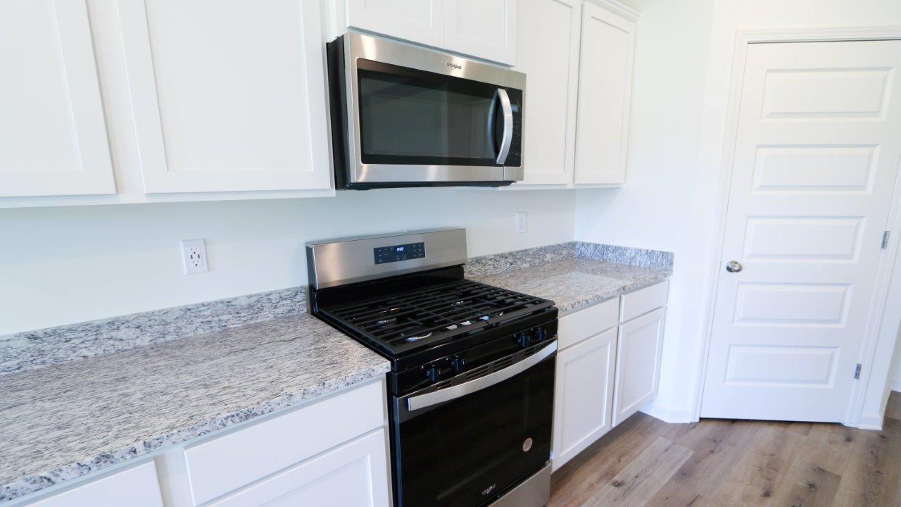 Modern kitchen with white cabinets, granite countertops, and stainless steel appliances.