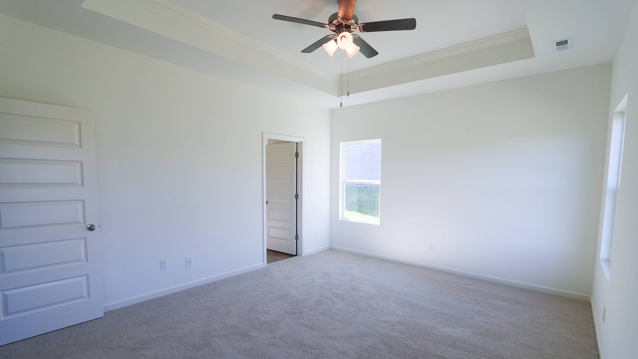 Empty room with carpet, white walls, ceiling fan, and a window.