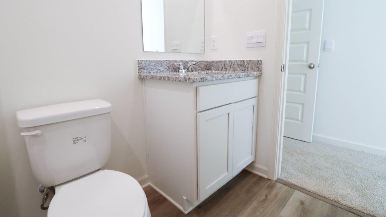 Modern bathroom interior with a white toilet and a vanity cabinet with a granite countertop.