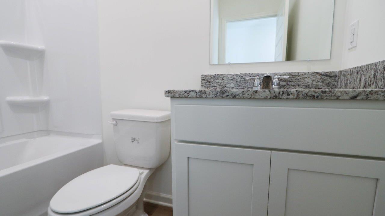 Modern bathroom interior with white toilet and vanity with granite countertop.