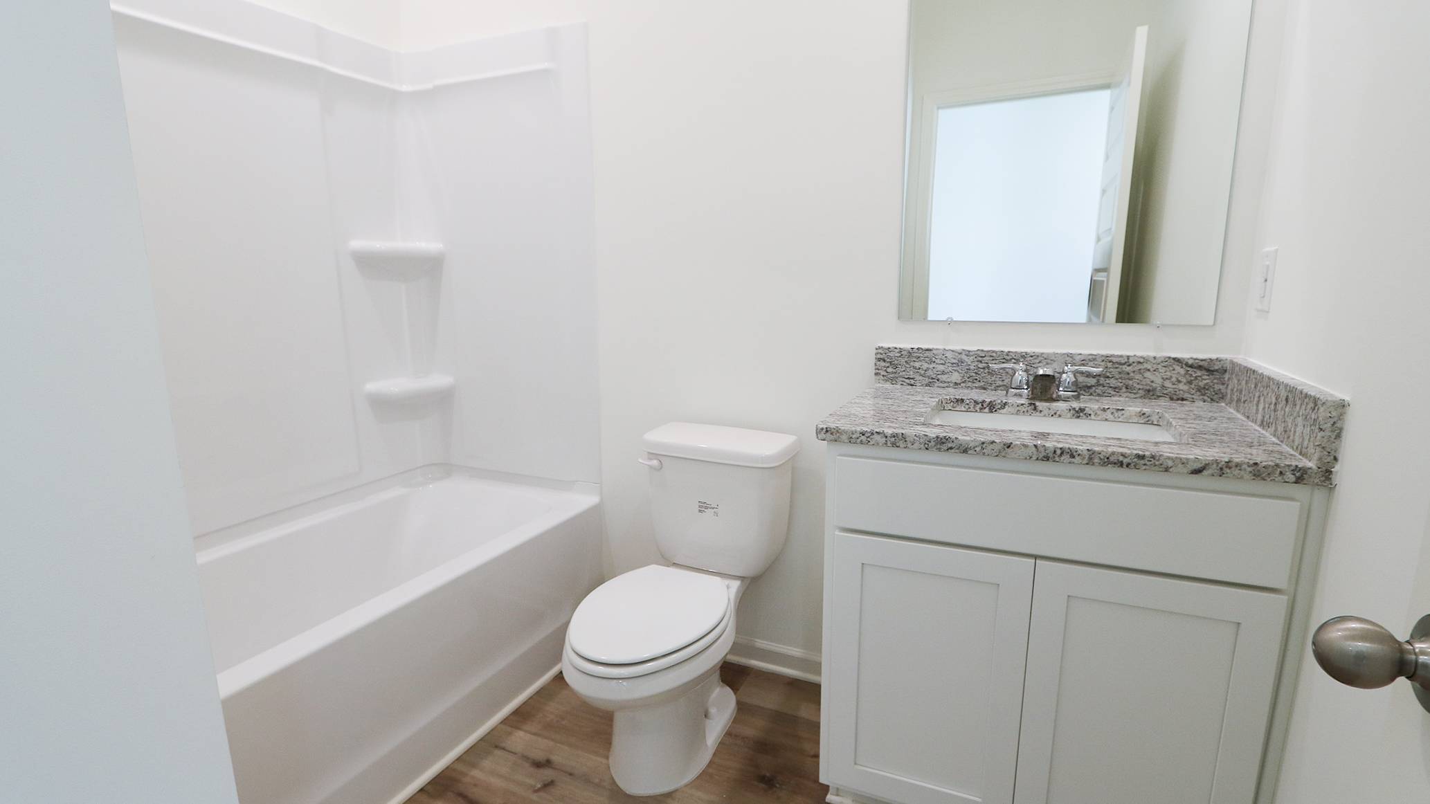 Modern bathroom interior with a bathtub, toilet, and sink with cabinet.