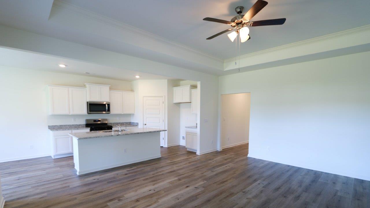A modern kitchen with white cabinets, granite countertops, and wood flooring.