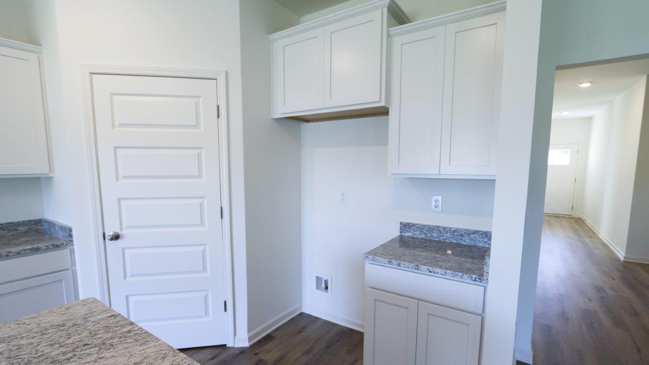 Modern kitchen corner with white cabinets, granite countertop, and wooden floor.
