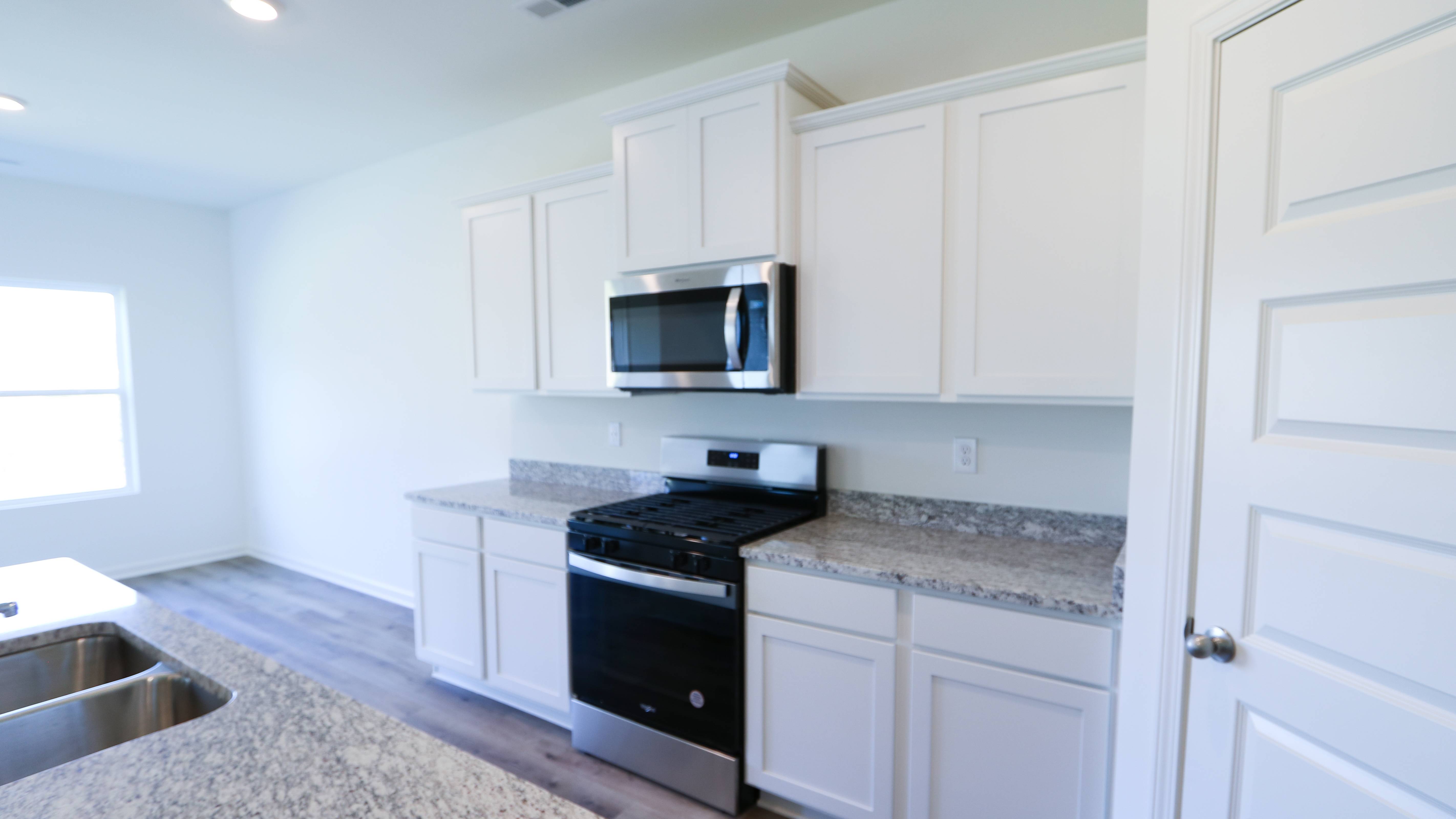 Modern kitchen interior with white cabinets, granite countertops, and stainless steel appliances.