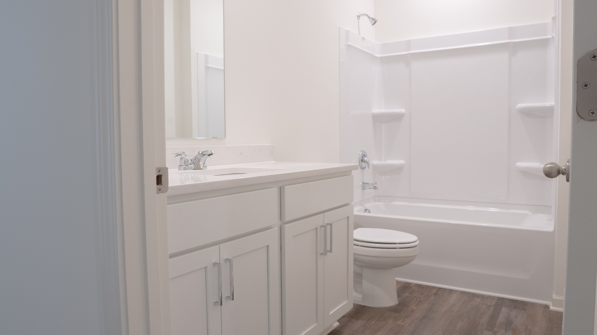 Low-angle shot highlighting the contrast between the wood-finish floors and the sleek double vanity.