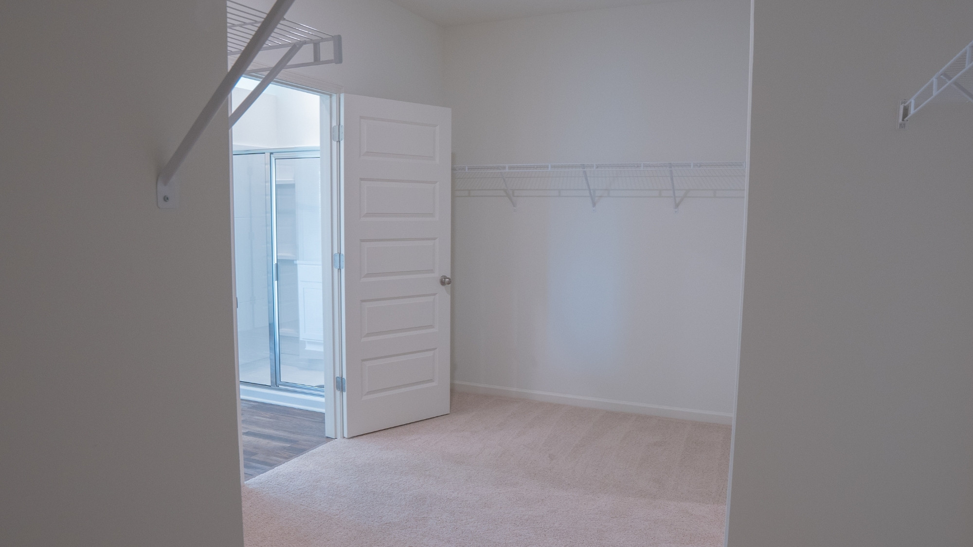 Shot from the entrance of the bathroom, showing the spacious layout and warm wood-tone flooring throughout.