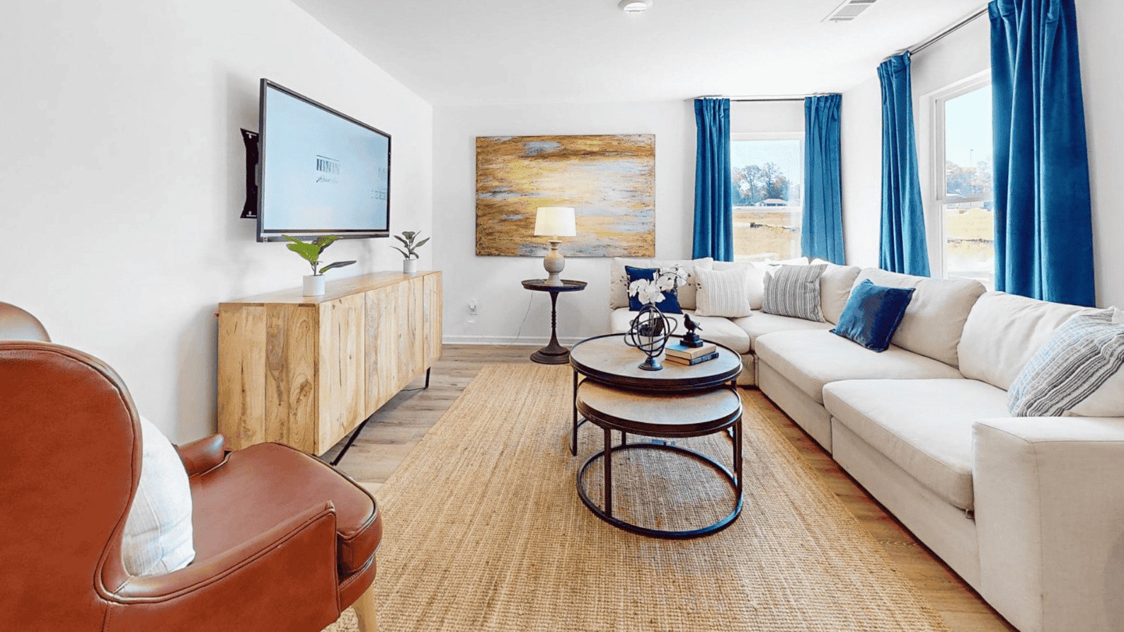 Open living room with a couch, coffee table and 1 chair and right off the living room is the kitchen and dining area