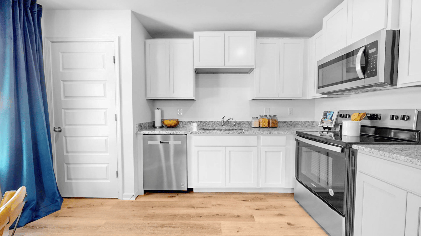 The kitchen is a spacious open concept area with stainless steel appliances. A dining table is situated next to a window, providing a pleasant dining experience. Additionally, there is a convenient walk-in pantry for storage and organization.