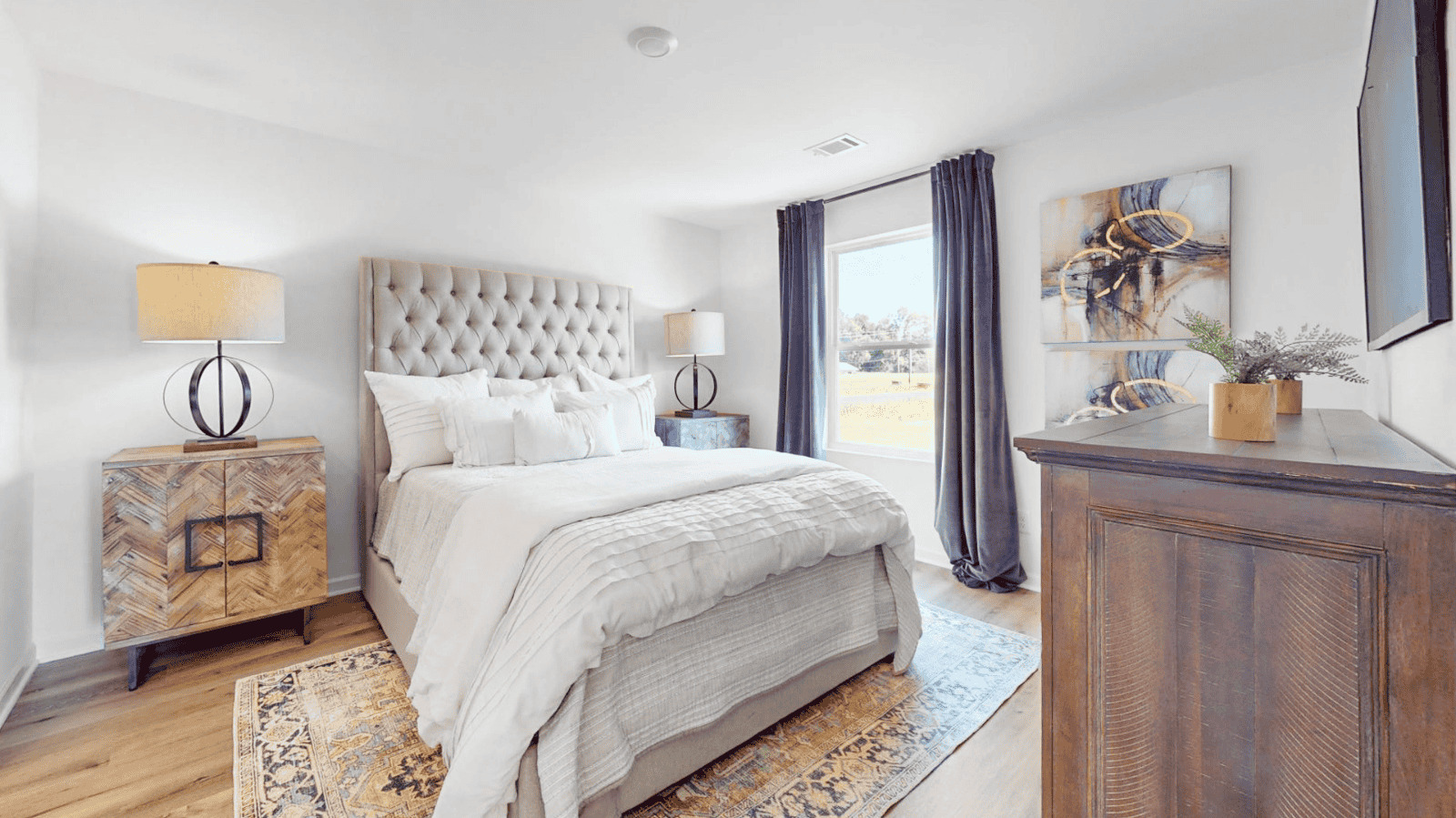 The spacious primary bedroom features a generously-sized king bed, two nightstands, and a large double window overlooking the backyard. It also provides convenient access to the primary bathroom and a walk-in closet for added comfort and functionality.