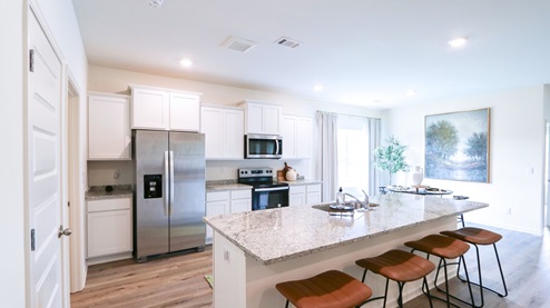 Destin – Kitchen – 1 – the open concept kitchen features a large island, white cabinets, stainless steel appliances and opens the full breakfast nook