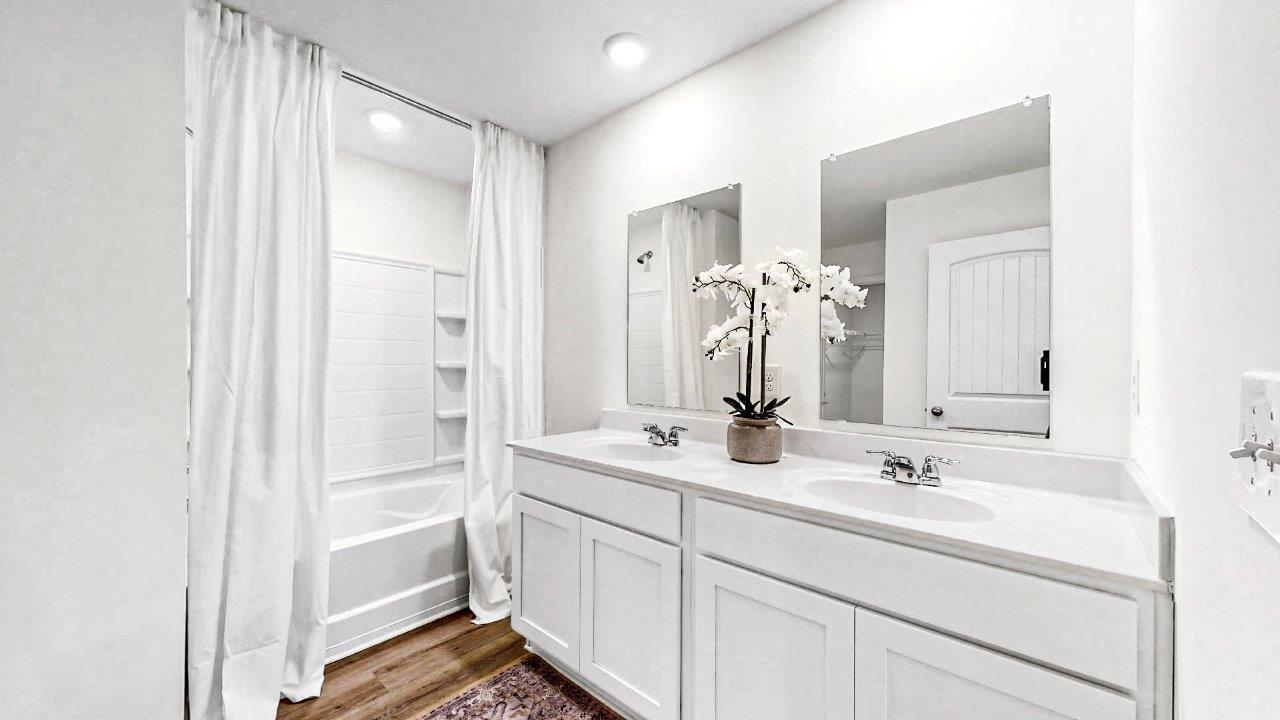 The spacious primary bathroom includes a large walk-in area with a double vanity equipped with two sinks. Additionally, it boasts a luxurious walk-in shower for added comfort and convenience.