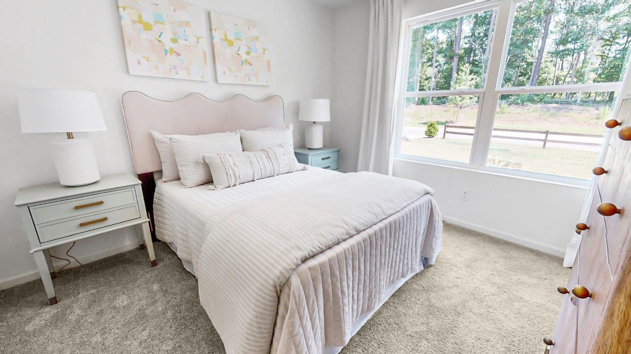 The third bedroom is located at the front of the house. It is furnished with a bed accompanied by two nightstands and a dresser.