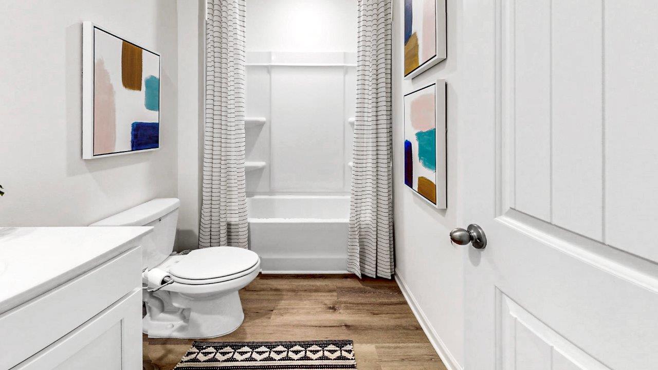 The second bathroom is located between bedroom 3 and 4. It is a full bathroom with a tub, shower, toilet, and vanity.