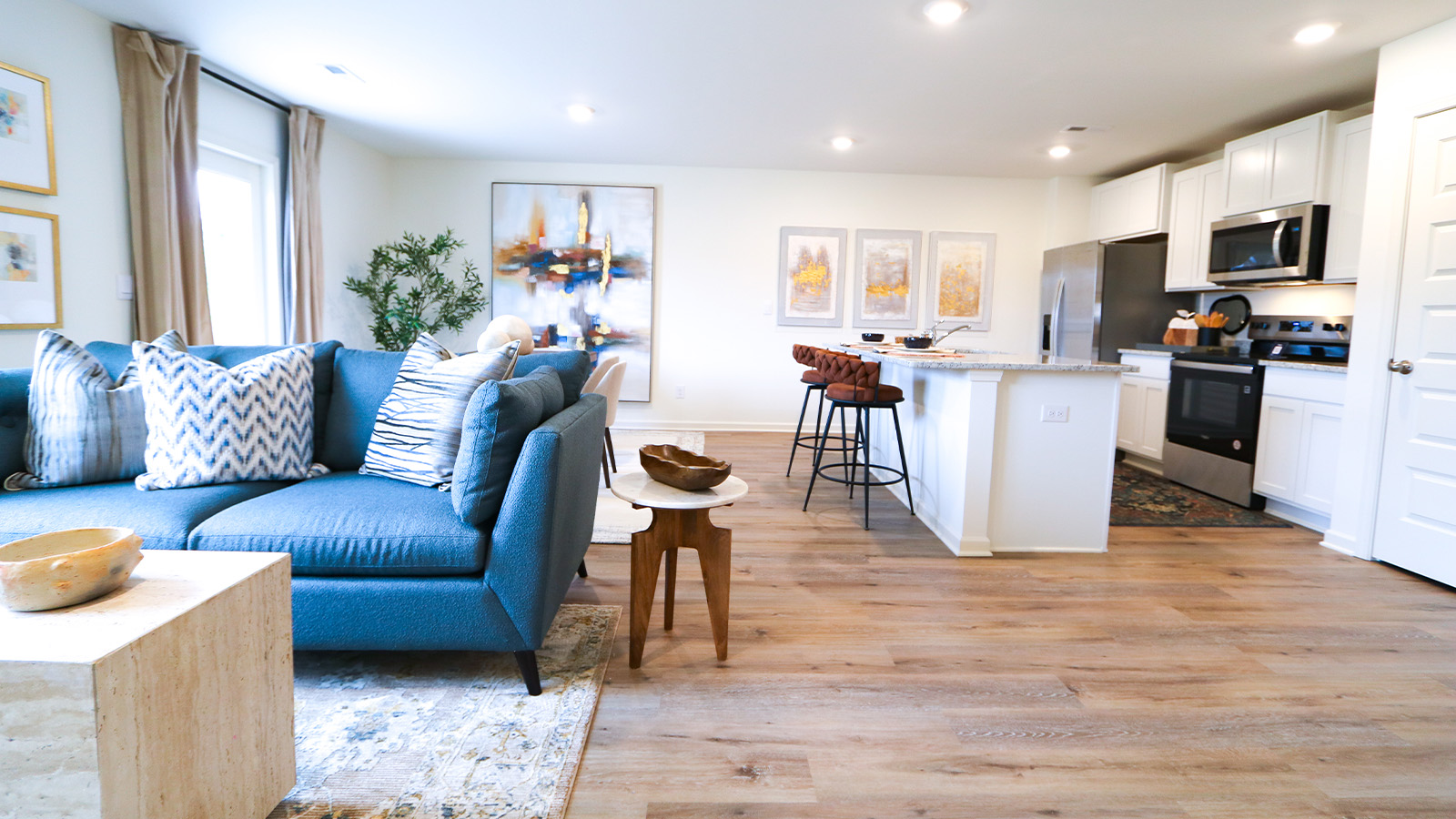 The living room is spacious and includes a comfortable couch, two poofs, a coffee table, a media console, and an accent chair.