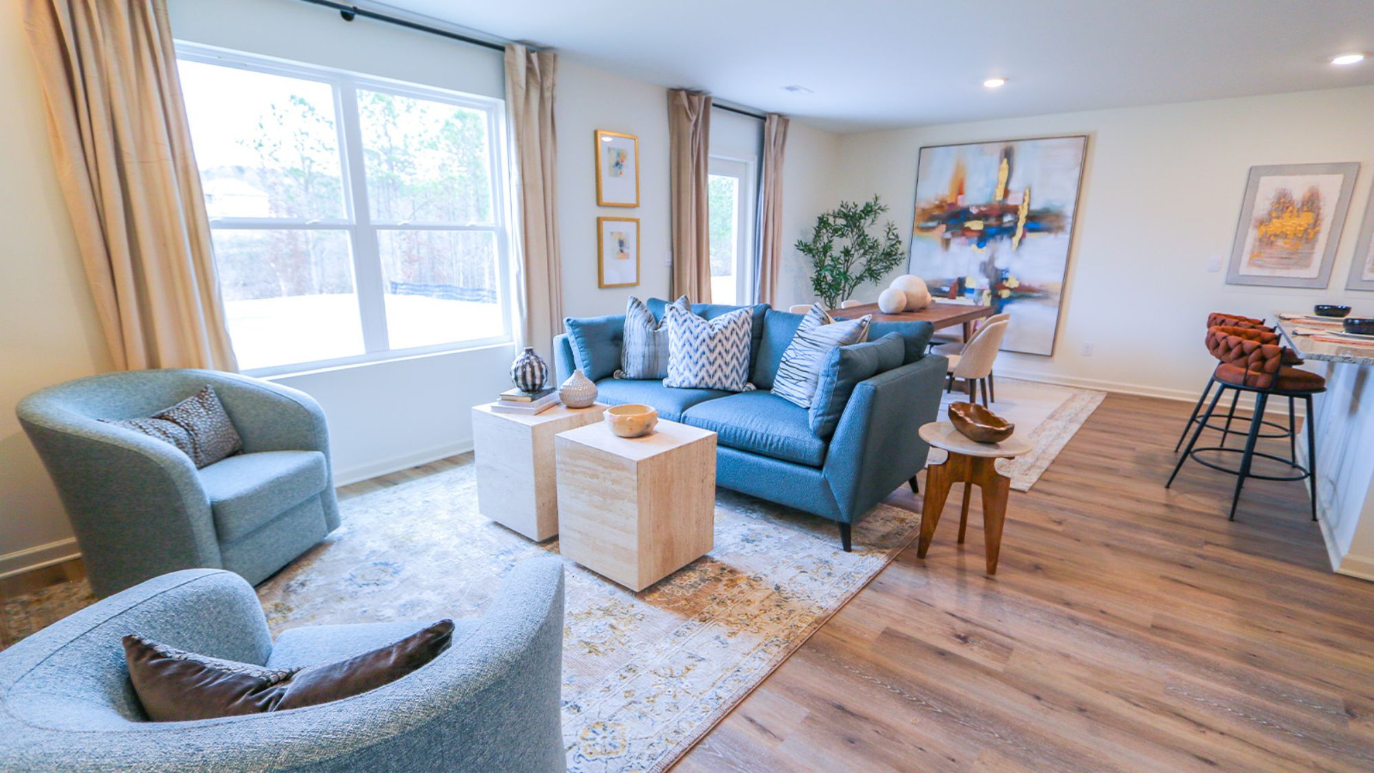 A spacious living room that features a couch, two poofs, a coffee table, a media consol and an accent chair.