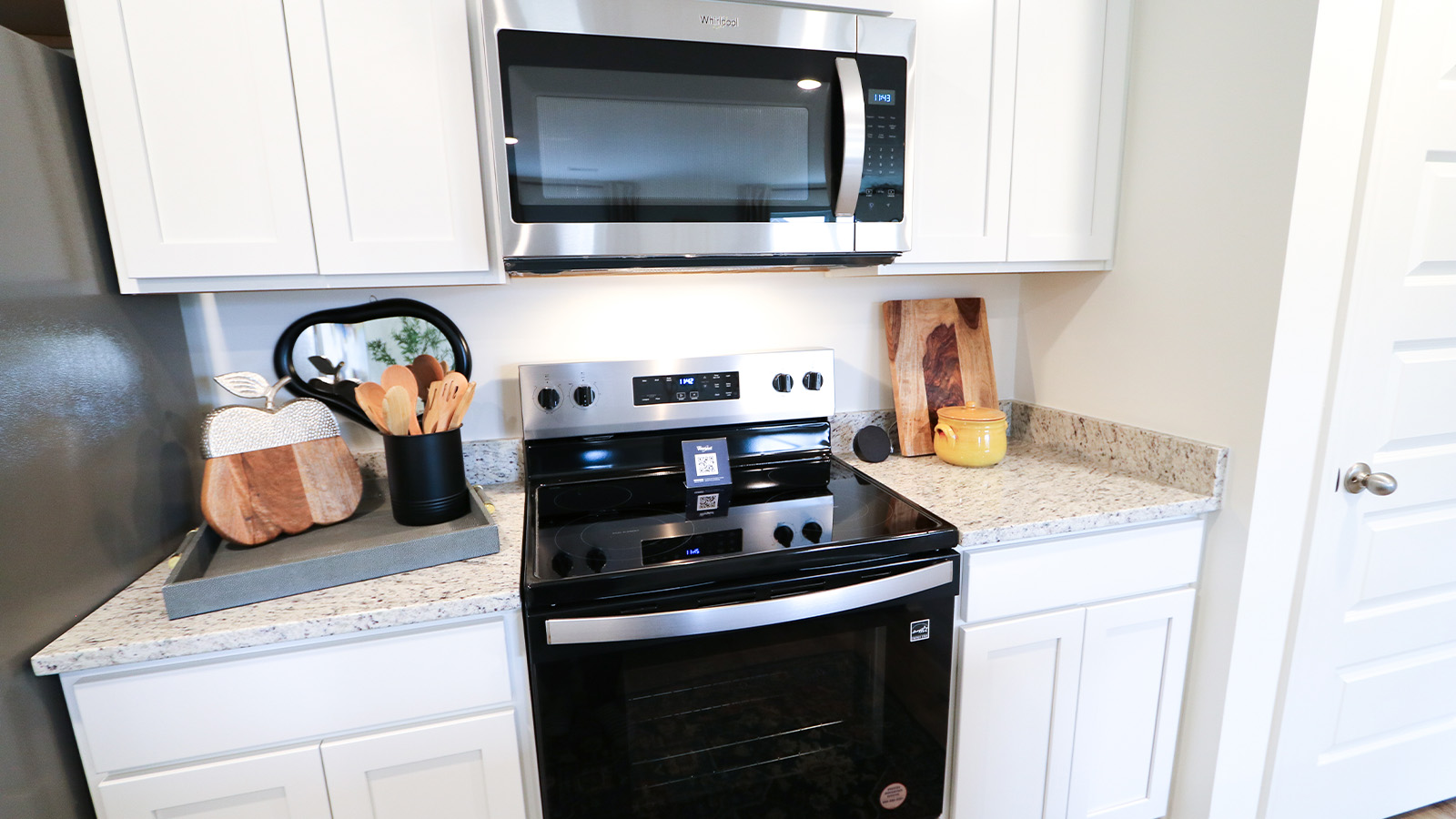An open concept kitchen that opens to the dining room and the living room features an oversized kitchen island with 3 barstools, stainless steel appliances, white cabinets and a pantry.