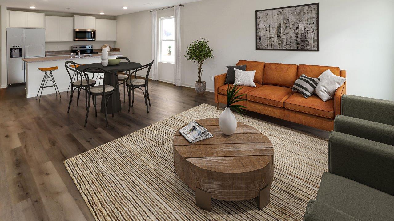 A contemporary living room featuring an open kitchen and dining area, showcasing modern furnishings and a spacious layout.