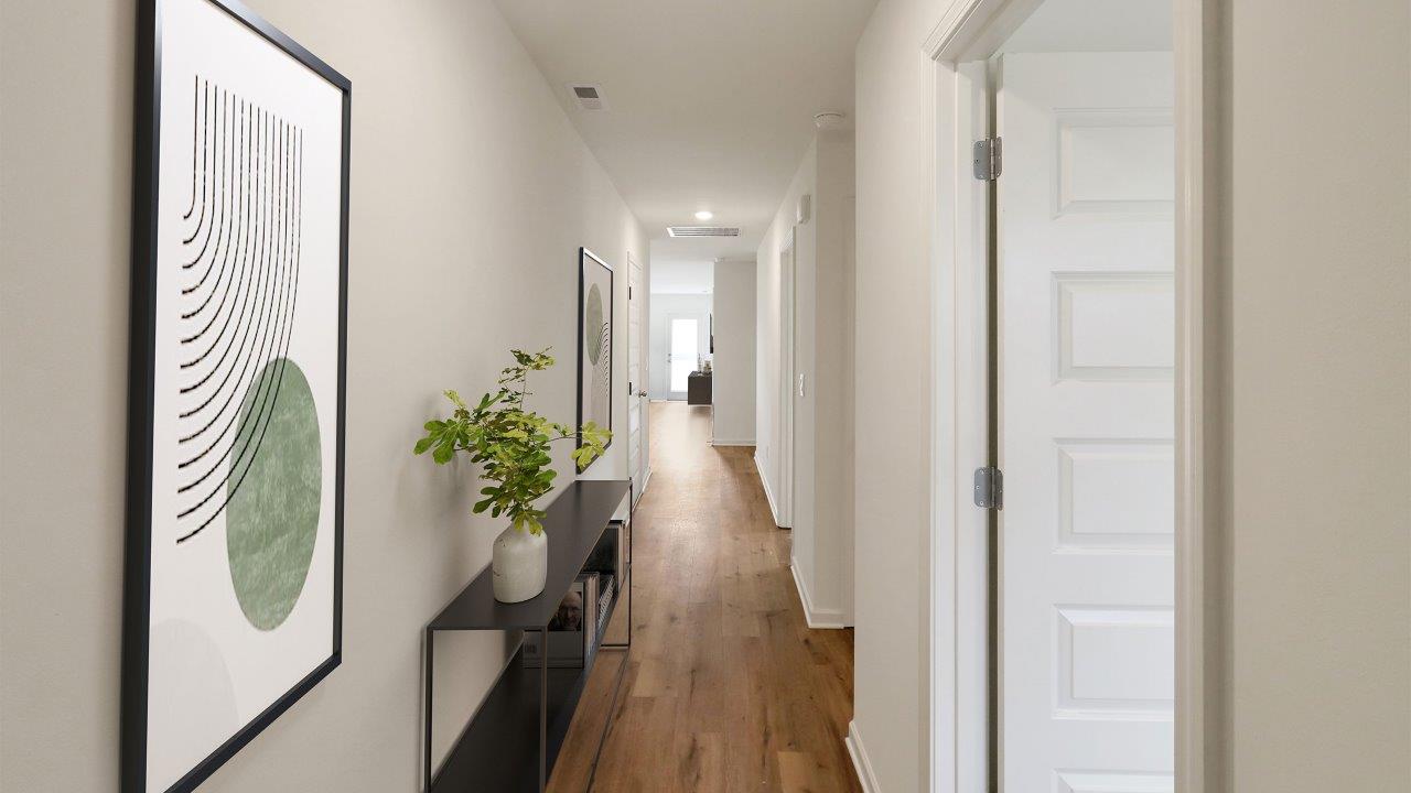 A hallway featuring a white door and a polished wooden floor, creating a bright and inviting atmosphere.