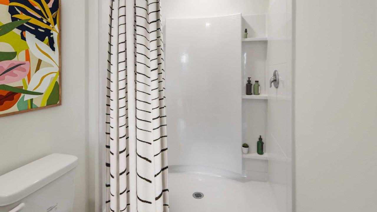 A clean bathroom featuring a shower curtain and a toilet, showcasing a simple and functional design.