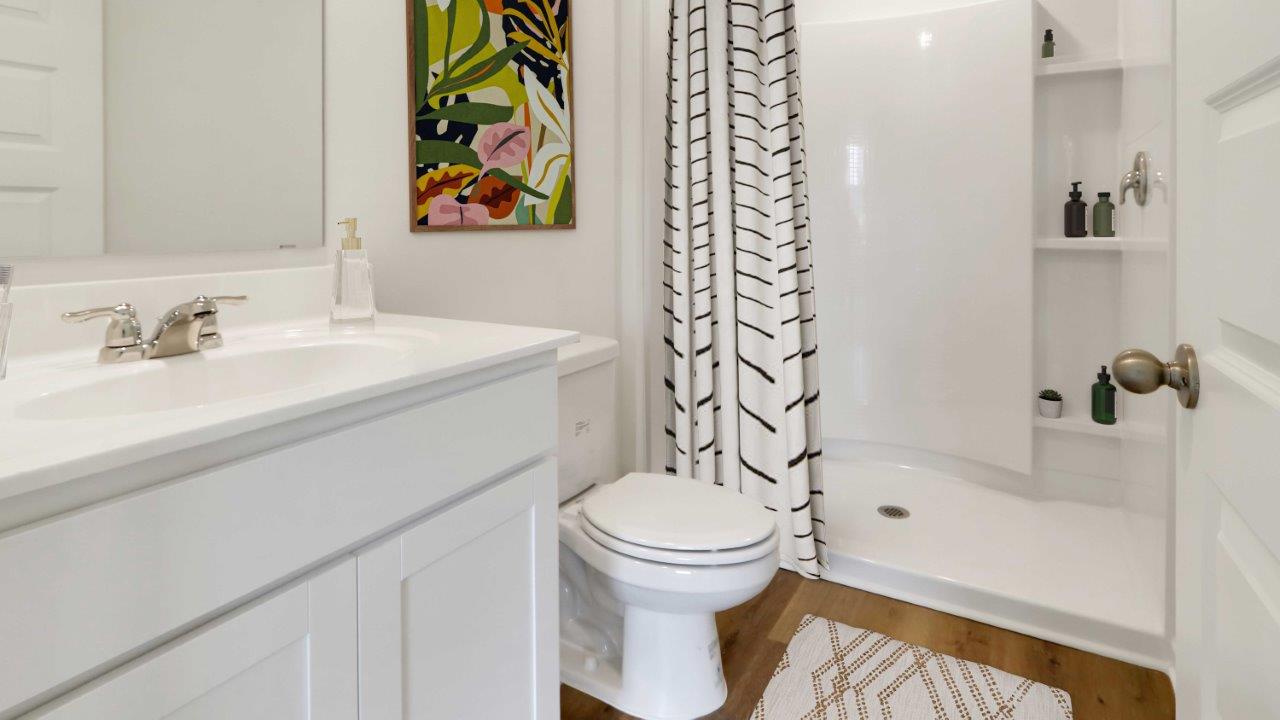 A clean bathroom featuring a shower, toilet, and sink, designed for functionality and comfort.